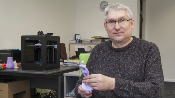 Piotr Burzyński, właściciel firmy Bardins z figurką wydrukowaną w technologii 3D. W tle pracuje drukarka Zortrax /fot.: ak / 